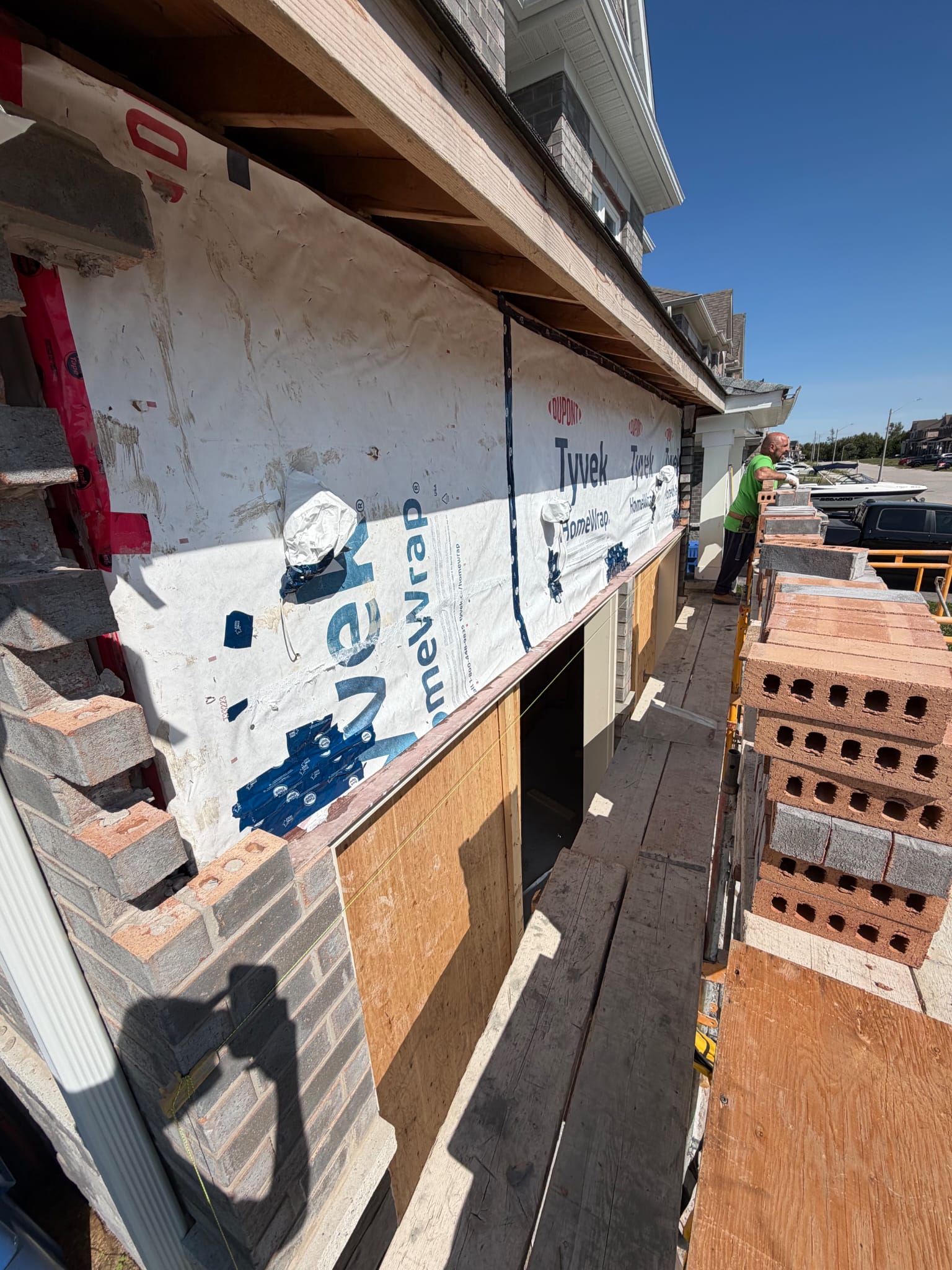 Brick veneer being laid over house wrap on a two storey house
