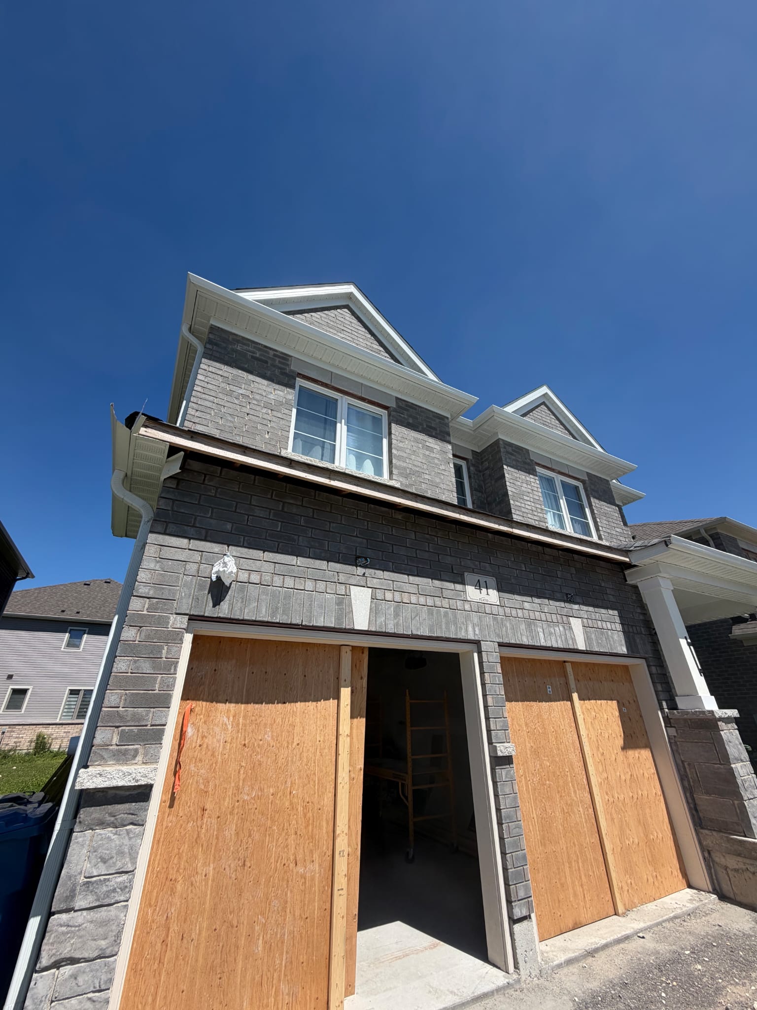 Front elevation of a grey brick house under construction
