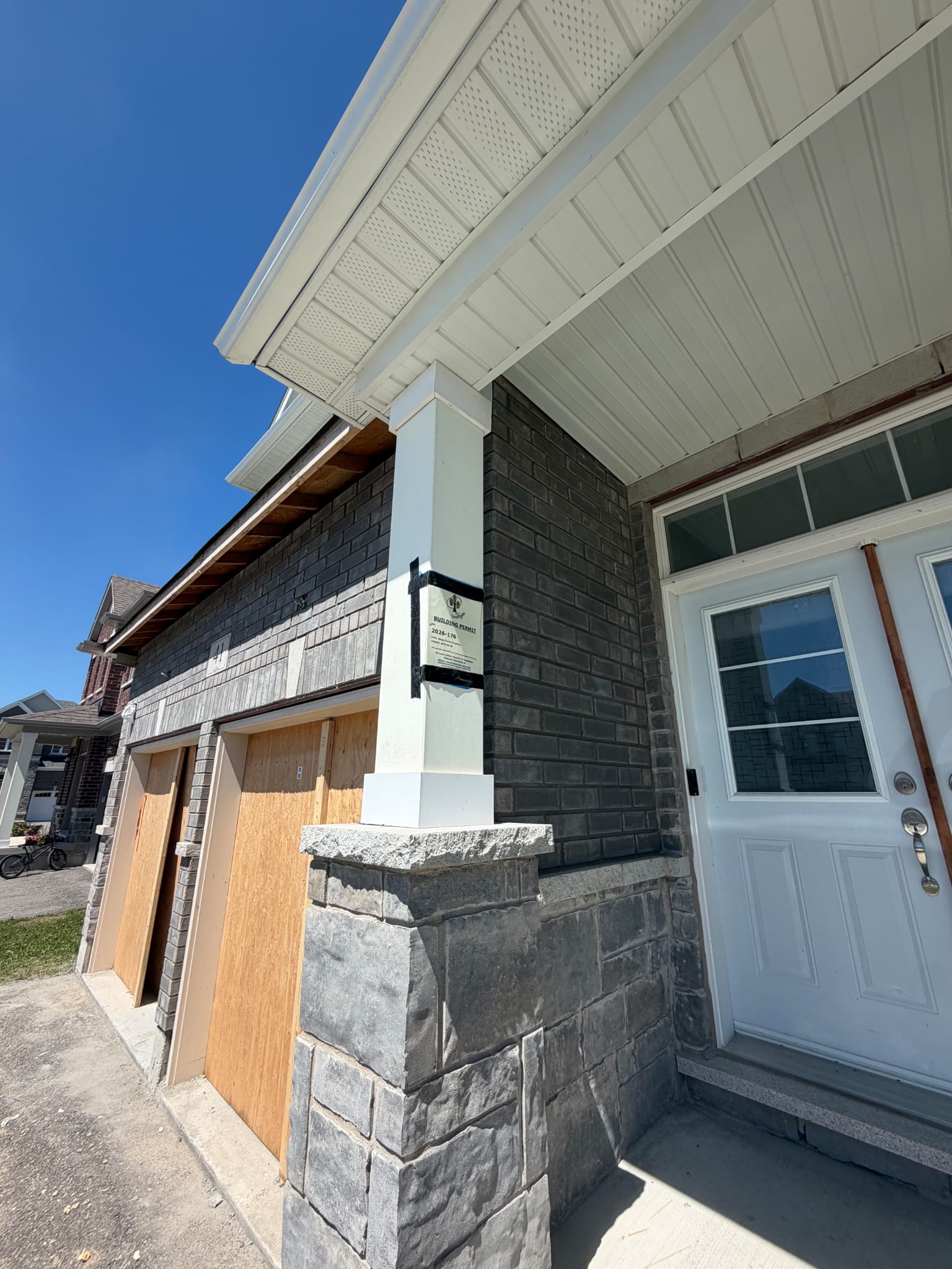 Stone veneer porch pier and white column on a permitted site