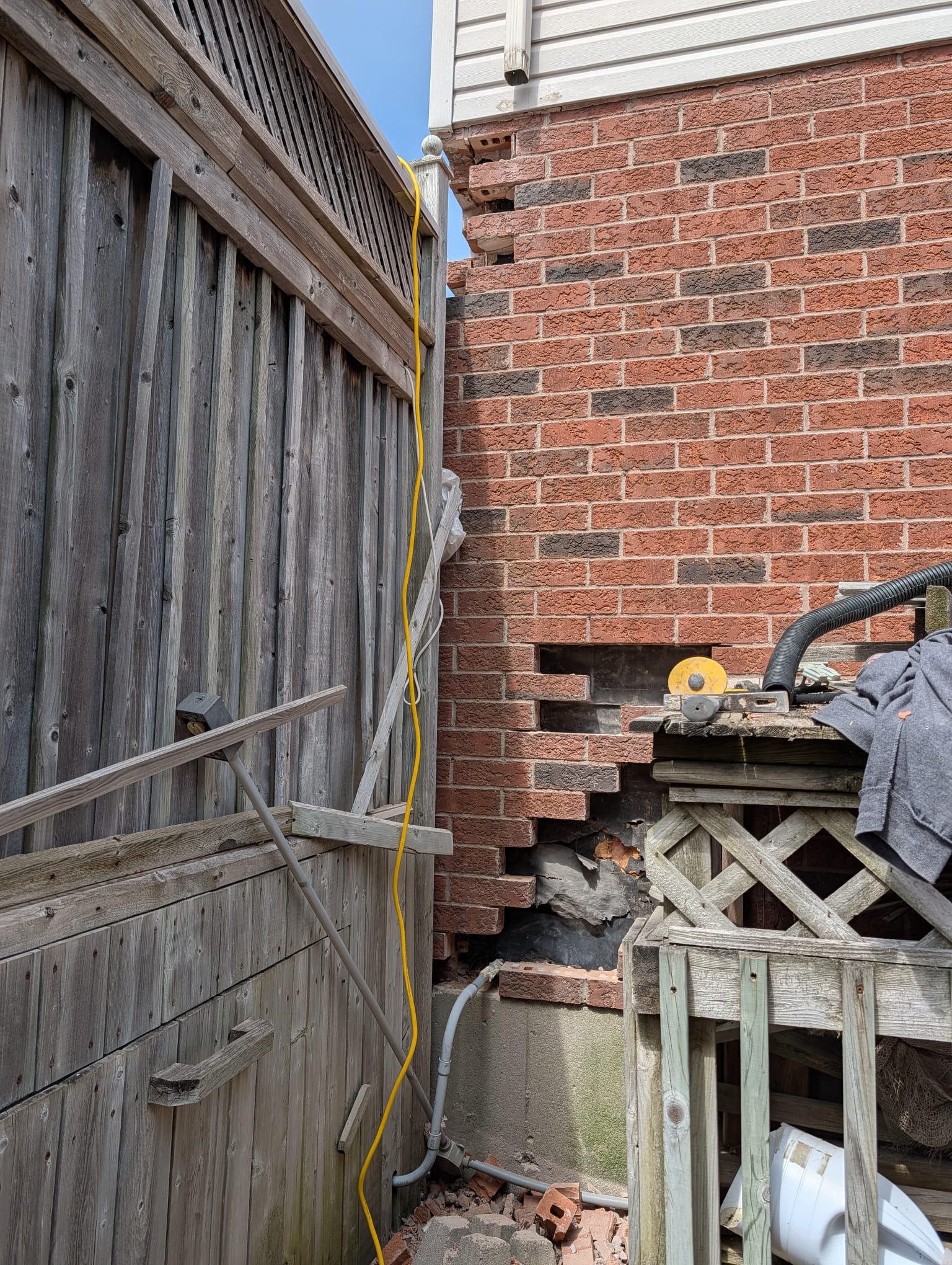 House corner with bricks removed in a toothed pattern and tar paper exposed