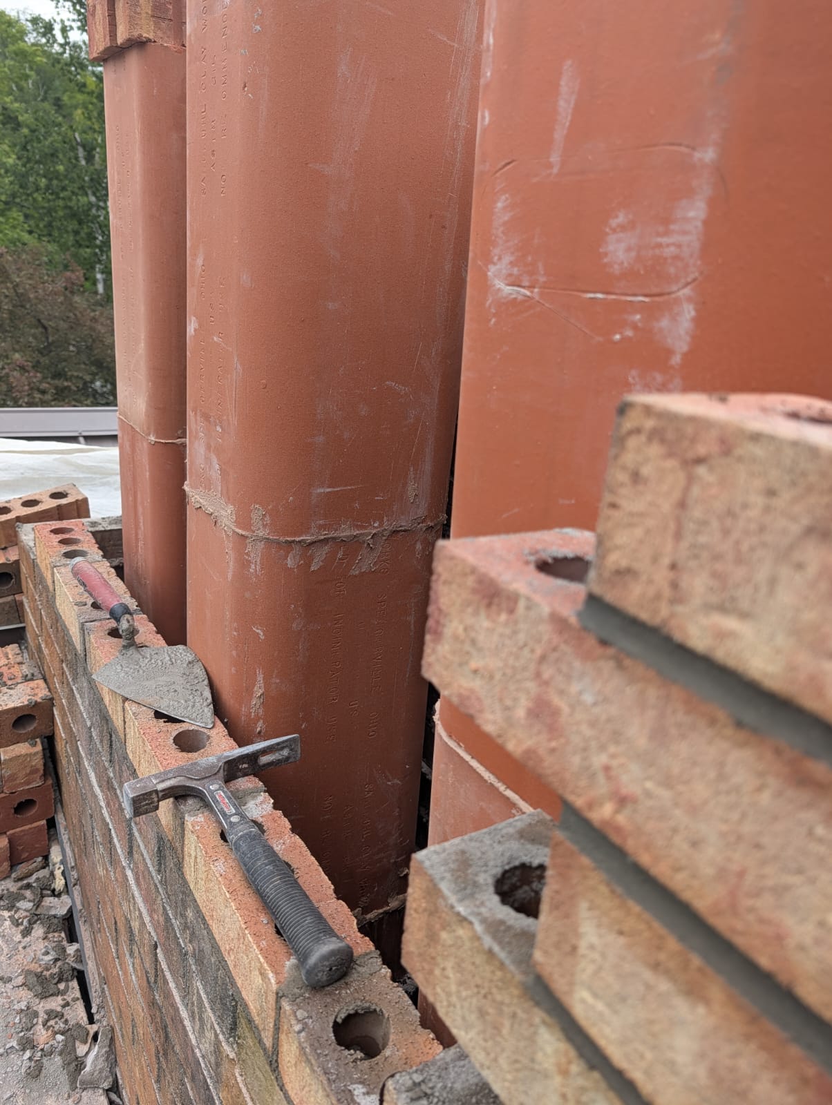 Clay flue liners and masonry tools laid out on a job site