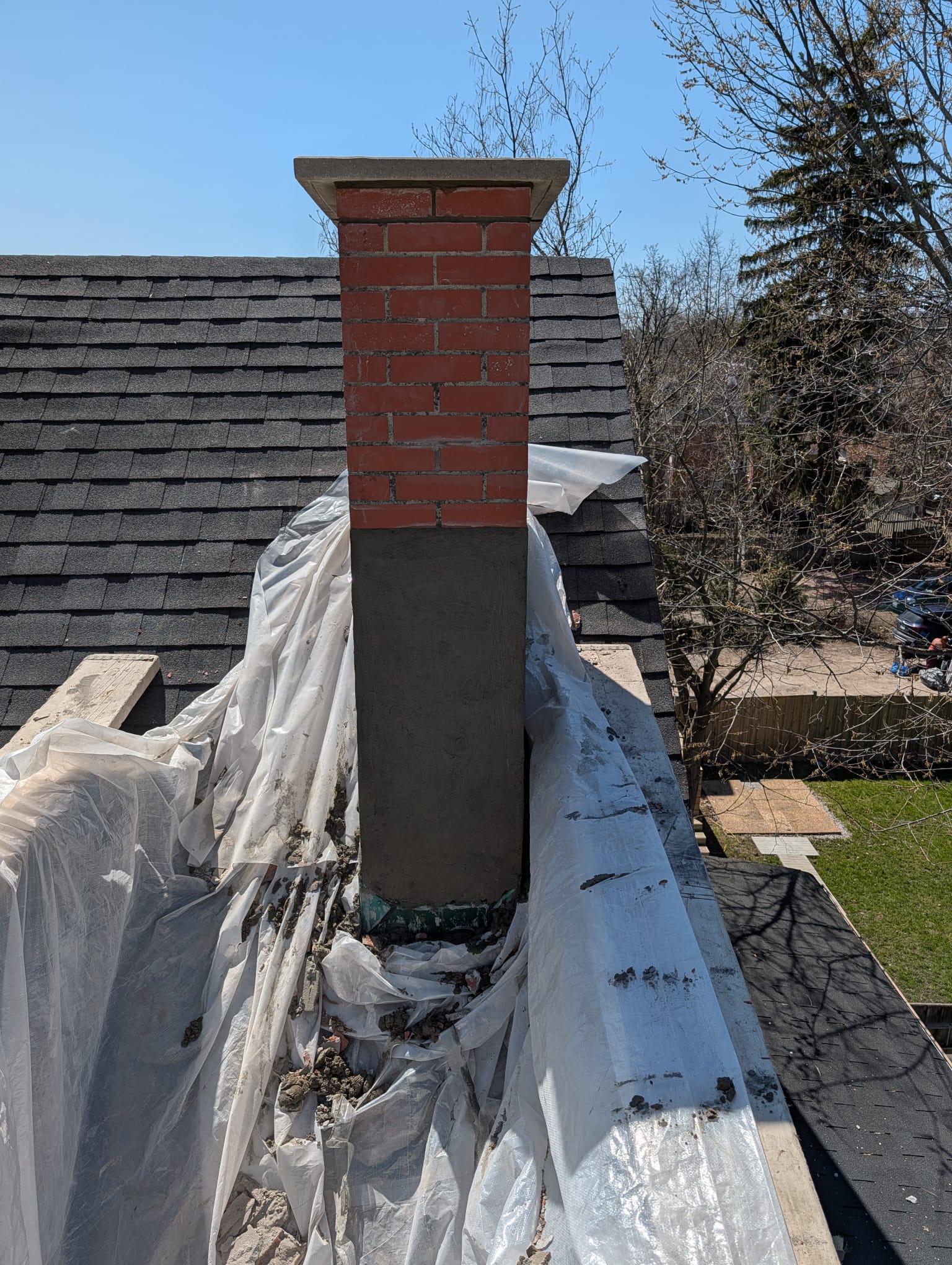 New brick at the top of a chimney above a parged chase, seen from the roof