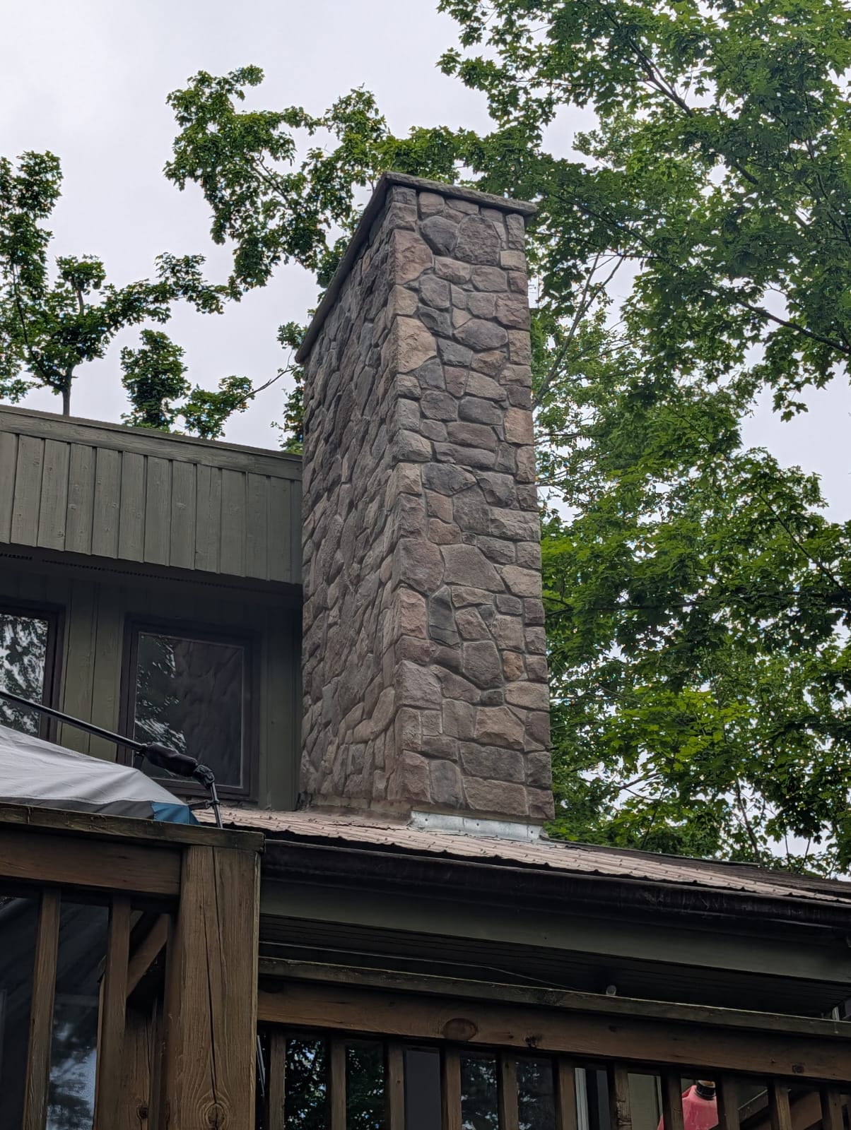 Chimney clad in stone veneer with a stone cap